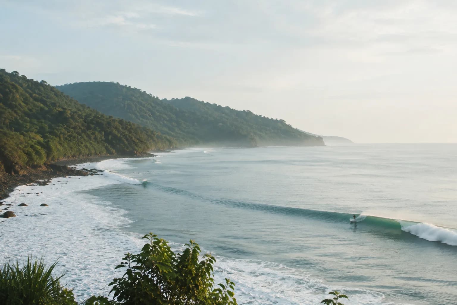 A long gentle wave wrapping beside lush green Java hills
