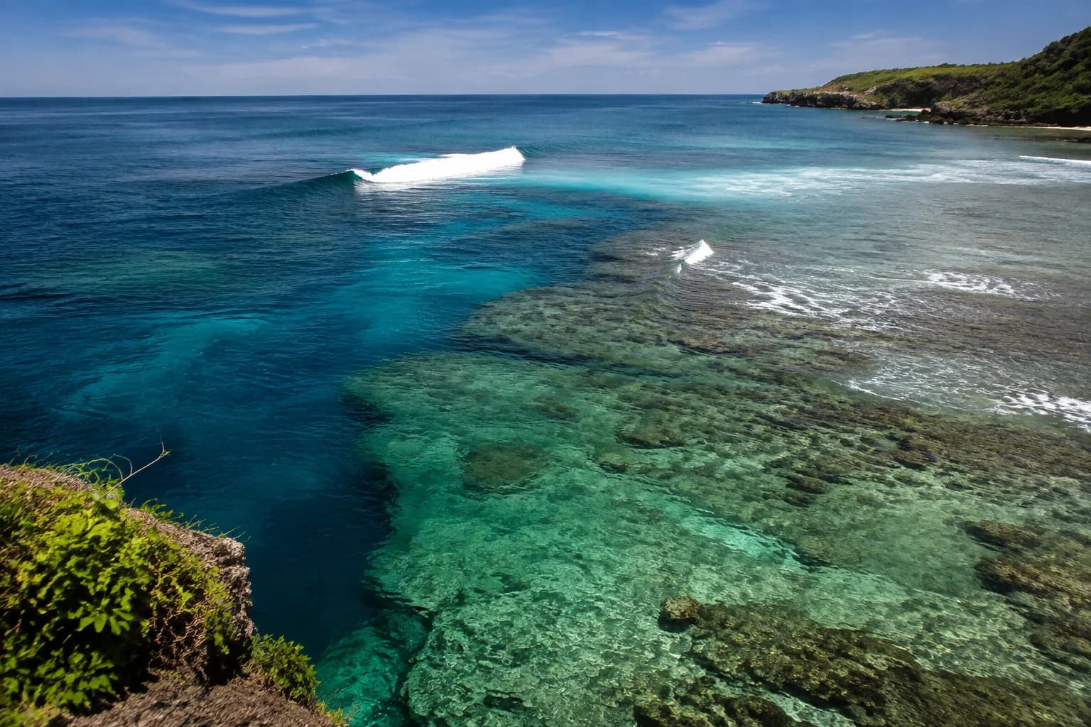 A calm reef channel beside lighter breaking water on an Indonesian coast