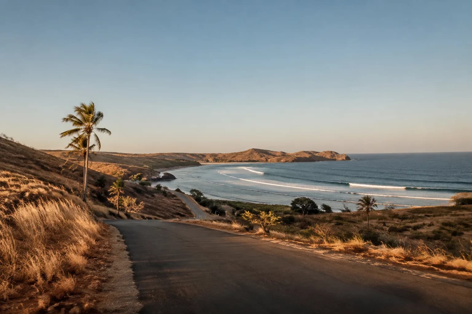 A remote Indonesian coastal road leading toward a quiet reef bay