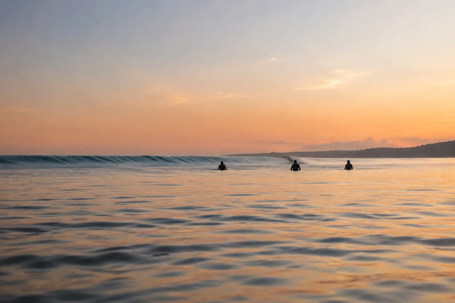Three surfers sitting with space between them in a calm Bali lineup